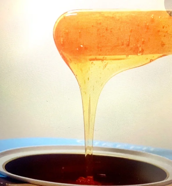 Golden wax lifted from a wax warmer on a spatula